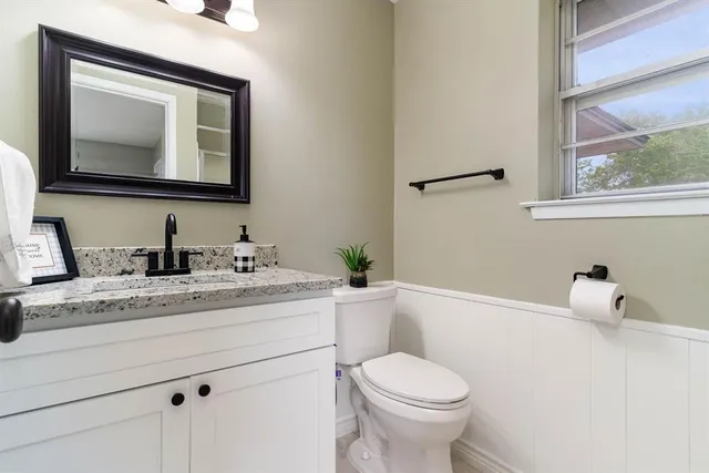 a bathroom with a granite countertop toilet sink and mirror