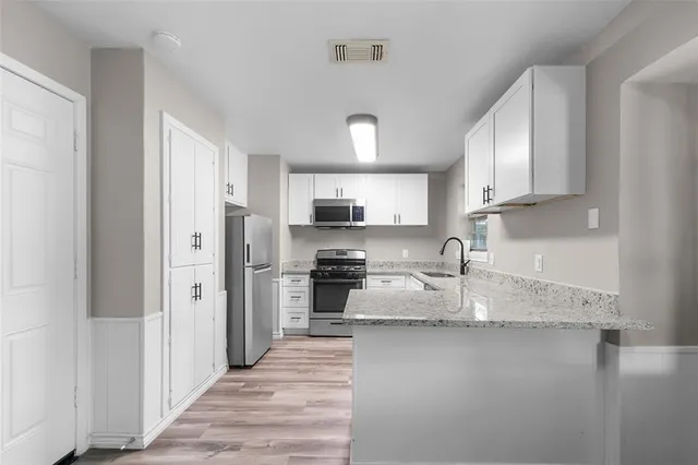 a kitchen with stainless steel appliances granite countertop a refrigerator a stove and a sink