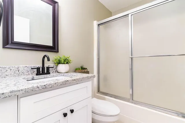 a bathroom with a granite countertop sink mirror vanity and toilet