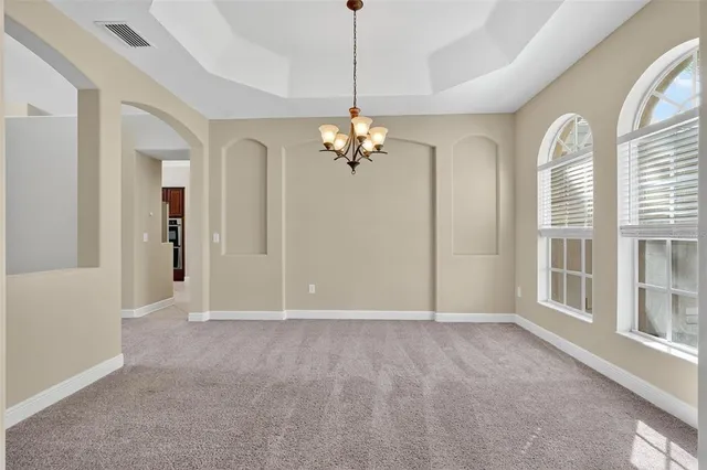 a view of a livingroom with a chandelier fan and windows