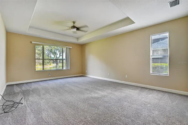 an empty room with windows and ceiling fan
