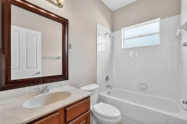 a bathroom with a granite countertop sink mirror toilet and bathtub