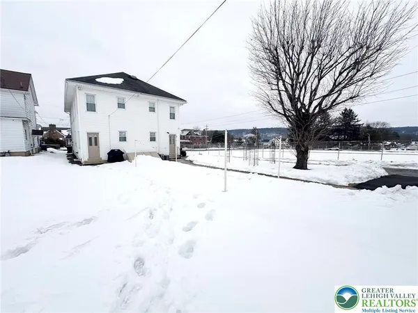 a view of a white house with snow on the road