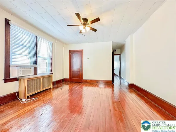 a view of an empty room with window and wooden floor