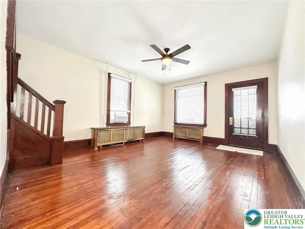 a view of an empty room with wooden floor and a window