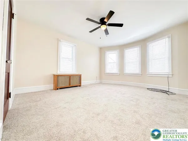 an empty room with windows and ceiling fan