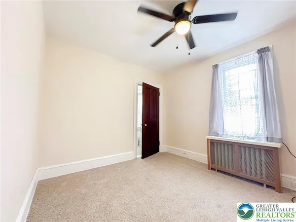 an empty room with windows and fan