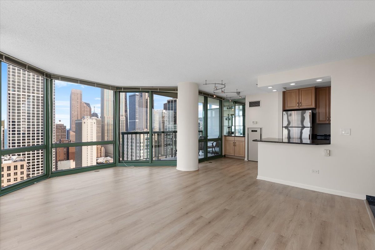 111 West Maple Street, Unit 3001 Chicago, IL 60610 - Photo 4 of 13 a view of an empty room with wooden floor and a window