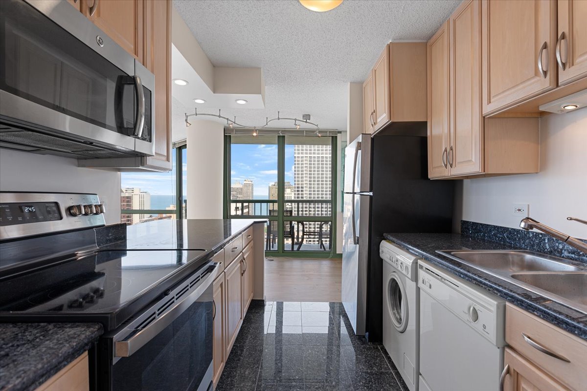 111 West Maple Street, Unit 3001 Chicago, IL 60610 - Photo 7 of 13 a kitchen with kitchen island granite countertop a sink a counter space stainless steel appliances and cabinets