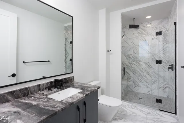 a bathroom with a granite countertop sink toilet and shower
