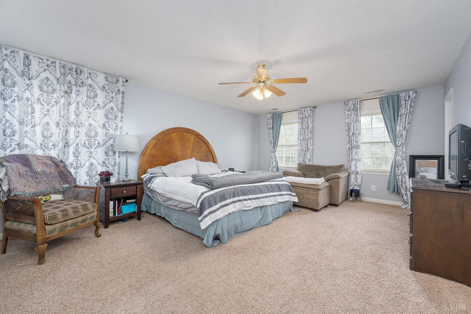 1498 Hooper Road Forest, VA 24551 - Photo 28 of 48 a spacious bedroom with a bed a couch and a chandelier