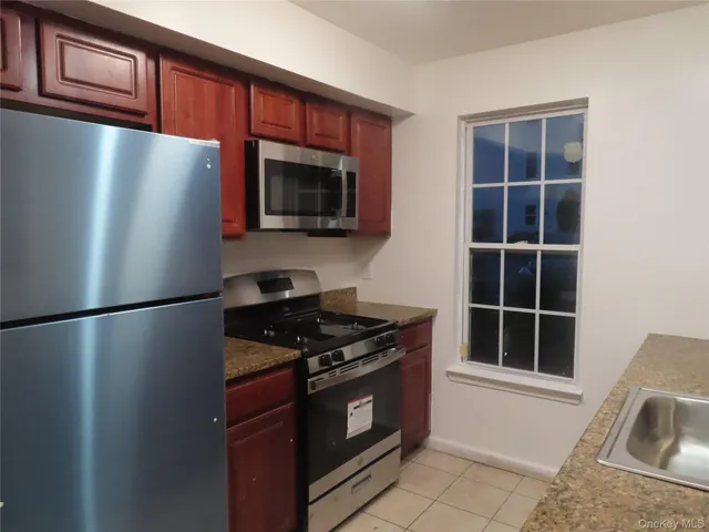 a kitchen with stainless steel appliances granite countertop a refrigerator a stove a sink and a microwave