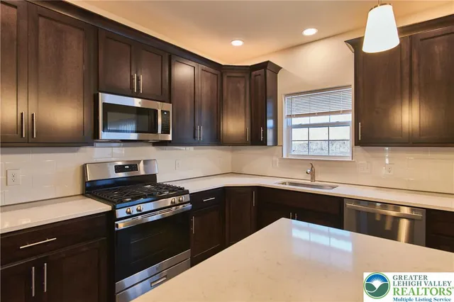 a kitchen with stainless steel appliances granite countertop a sink a stove a microwave and cabinets