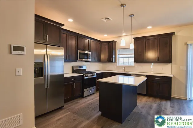 a kitchen with stainless steel appliances granite countertop refrigerator a sink a stove a microwave and wooden floor