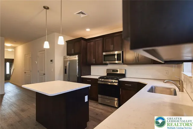 a kitchen with kitchen island a sink dishwasher a refrigerator and a stove with wooden floor