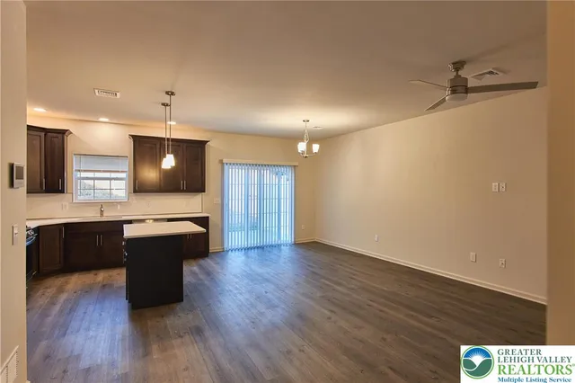 a large kitchen with a center island wooden floor and stainless steel appliances