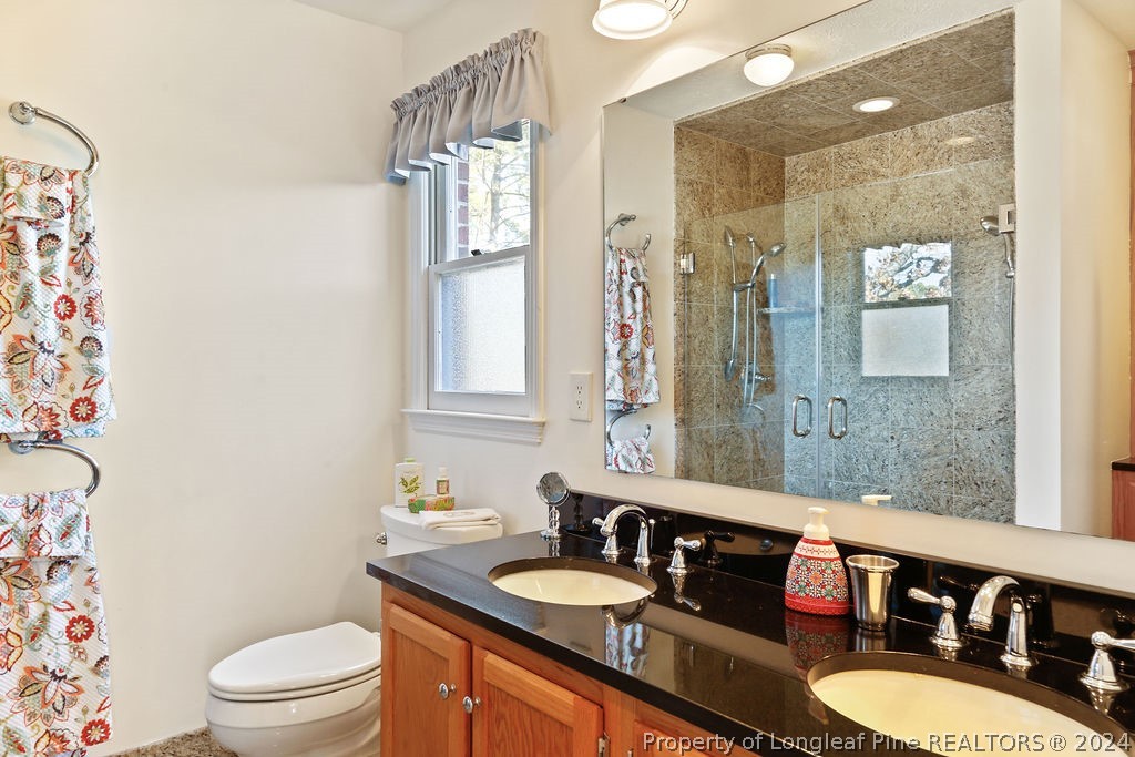 300 Shawcroft Road Fayetteville, NC 28311 - Photo 19 of 42 a bathroom with a granite countertop sink a toilet a mirror and shower curtain
