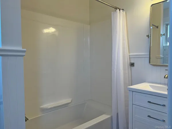 a bathroom with a tub a sink and mirror