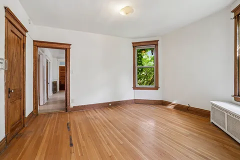 a view of an empty room with wooden floor and a window