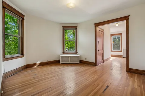 a view of an empty room with wooden floor and a window