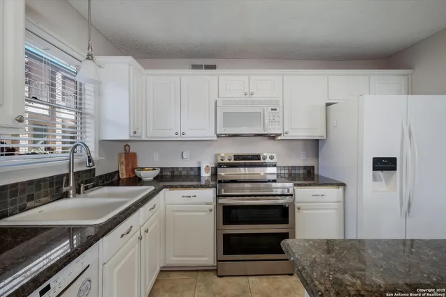 a kitchen with granite countertop a sink stainless steel appliances and cabinets