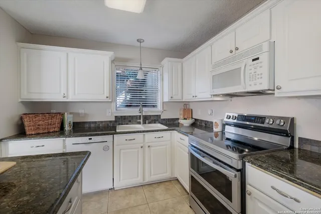a kitchen with stainless steel appliances granite countertop a stove sink and cabinets