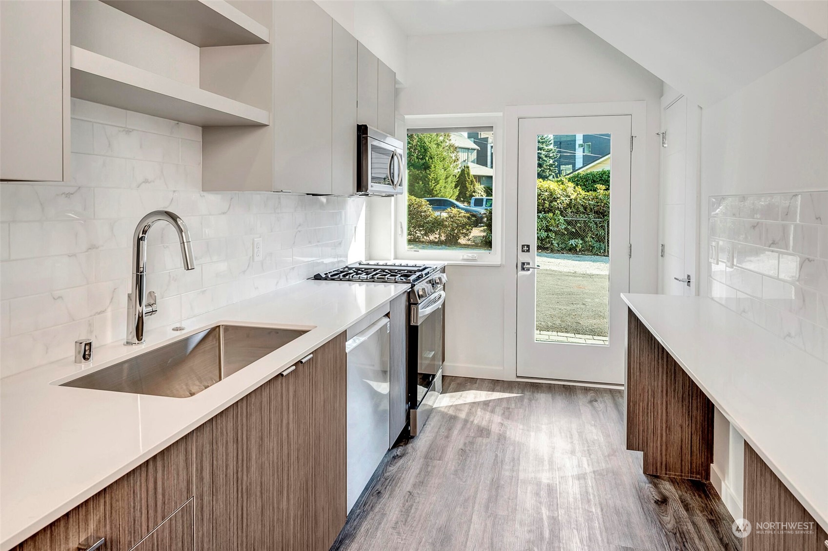 10170 Holman Road Northwest, Unit E Seattle, WA 98133 - Photo 2 of 12 a kitchen with kitchen island granite countertop a sink a counter space appliances and cabinets
