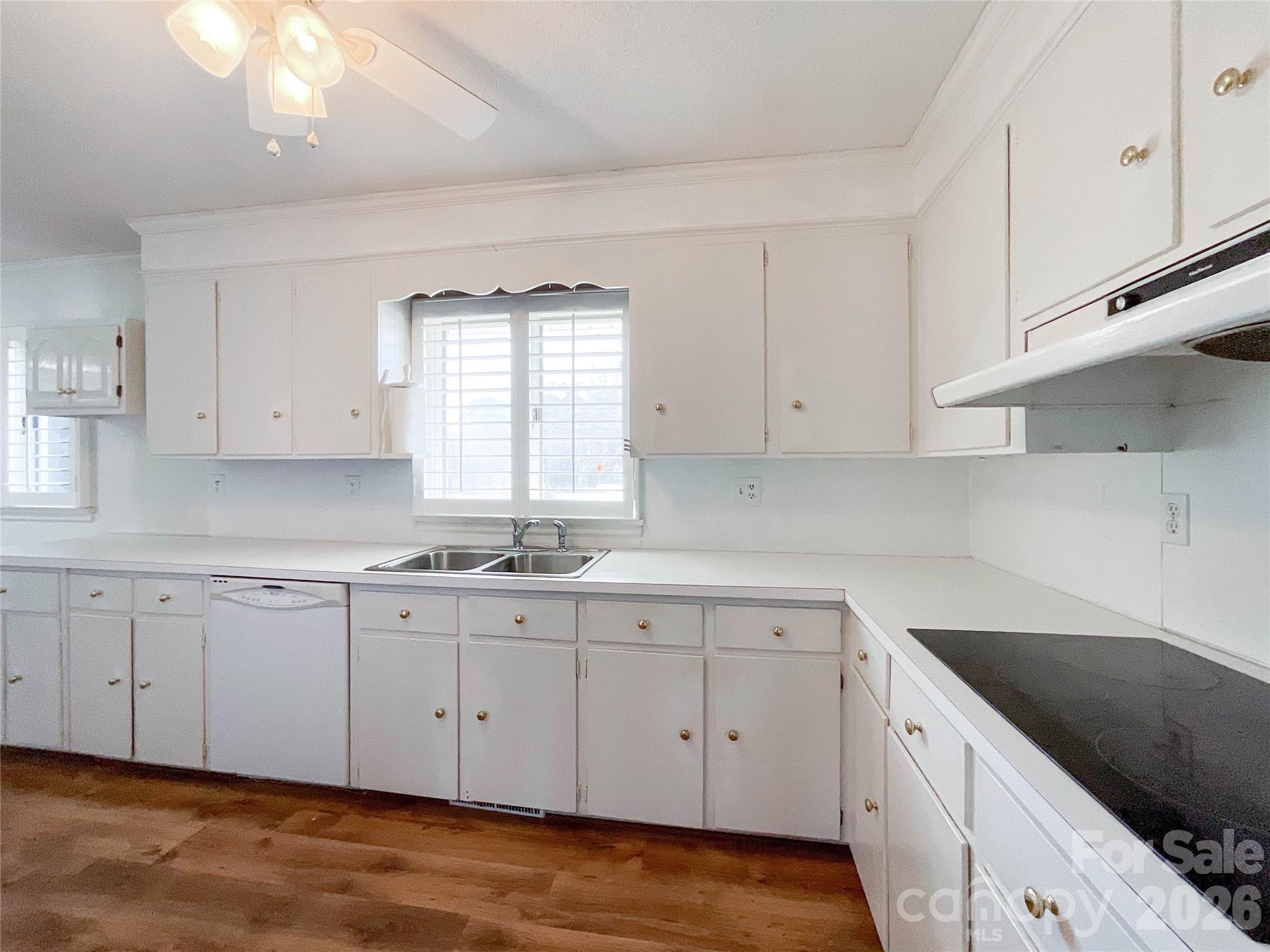 13909 Idlewild Road Matthews, NC 28105 - Photo 17 of 48 a kitchen with white cabinets white appliances sink and dishwasher with wooden floor