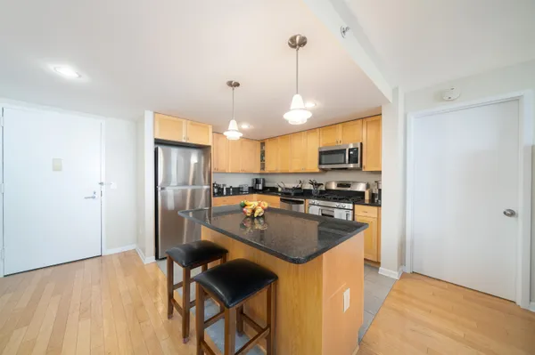 a kitchen with a refrigerator a stove a sink dishwasher a dining table and chairs with wooden floor