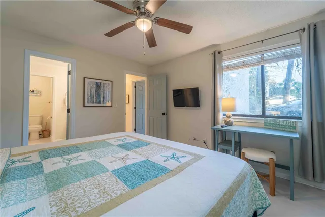 a bedroom with a bed and a chandelier with a flat tv screen