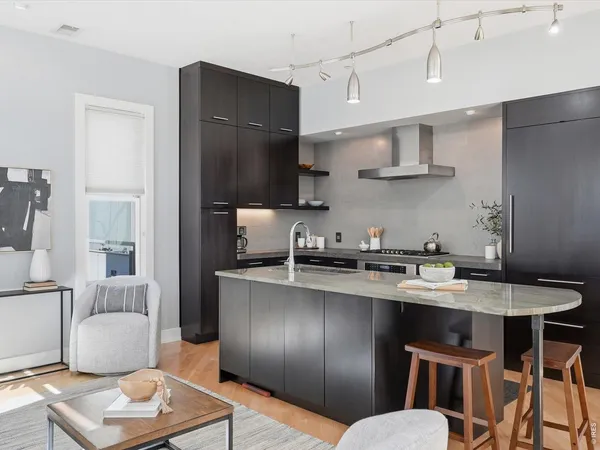 a kitchen with stainless steel appliances granite countertop a sink a stove a refrigerator and blue cabinets with wooden floor