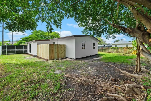 a backyard of a house with plants and large tree