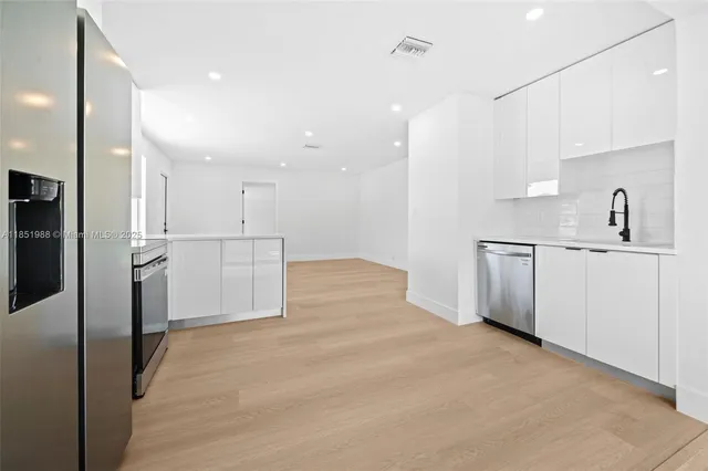 a kitchen with stainless steel appliances kitchen island a refrigerator sink and cabinets