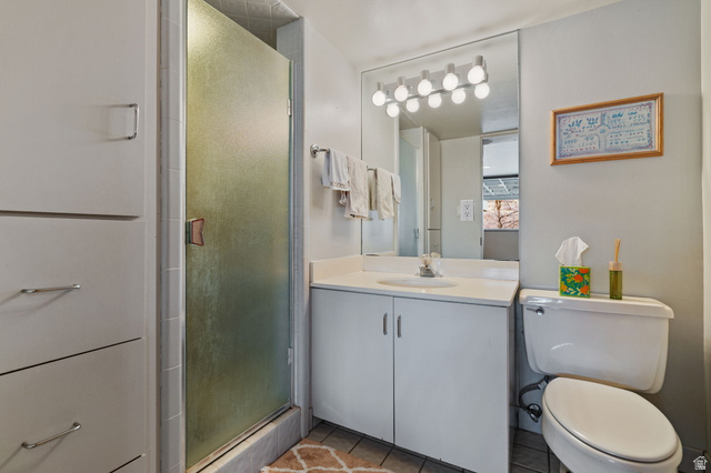1856 Fort Canyon Road Alpine, UT 84004 - Photo 22 of 49 Bathroom featuring a vanity with an integrated sink, a rectangular mirror with a multi-bulb light fixture, a toilet, and a shower with a frosted glass door