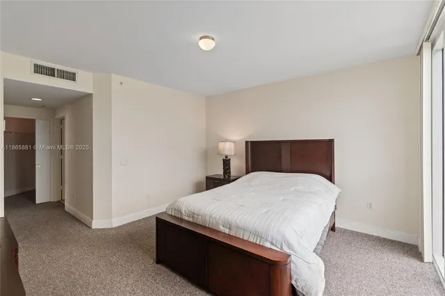 a bedroom with a bed and a flat tv screen on dresser