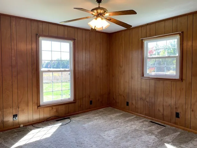 an empty room with windows and fan