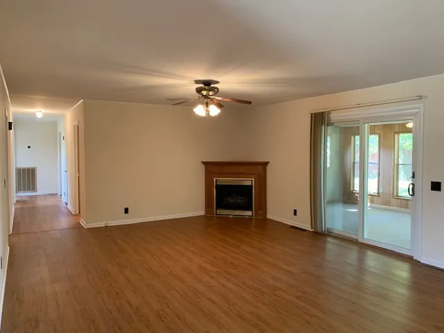 a view of an empty room with glass door and wooden floor