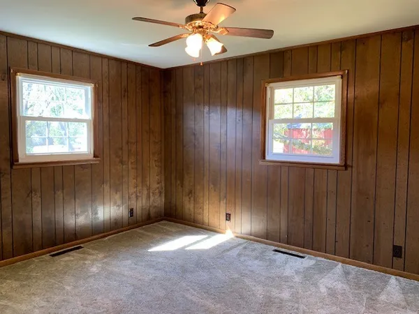 an empty room with windows closet and chandelier fan