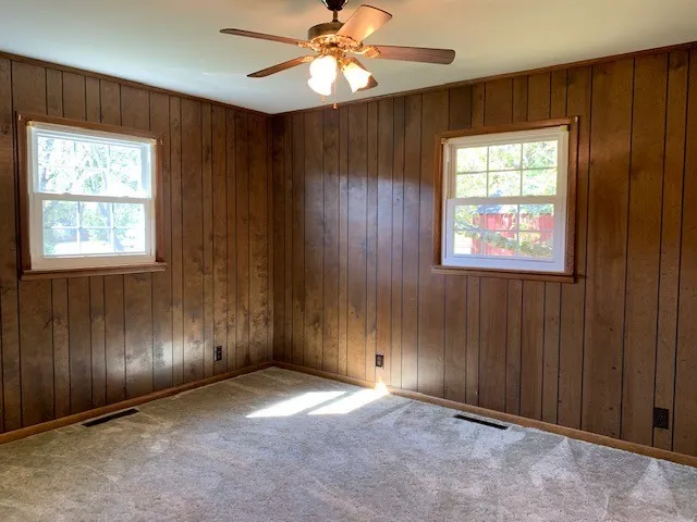 an empty room with windows closet and chandelier fan