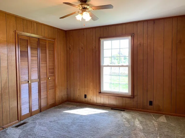 an empty room with windows chandelier fan and windows