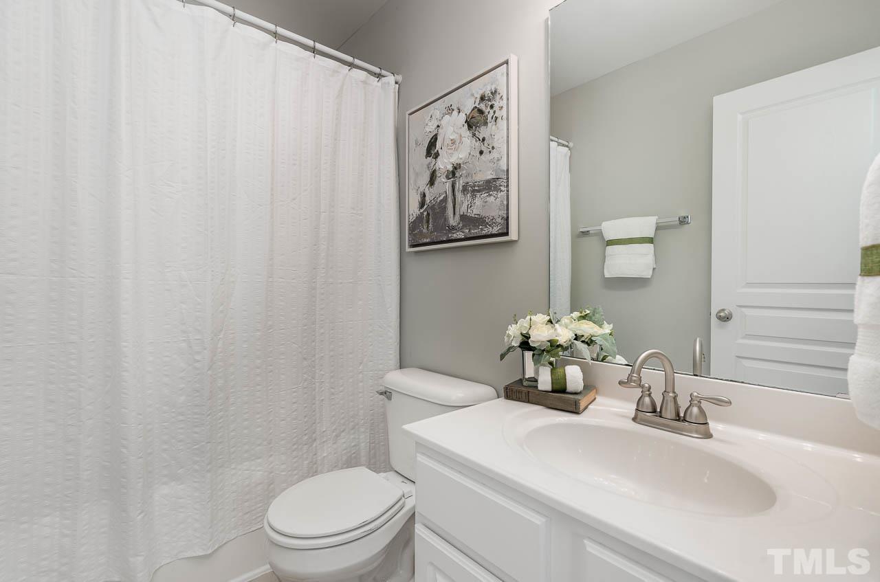 6022 Viking Drive Raleigh, NC 27612 - Photo 10 of 11 a bathroom with a toilet a sink and a mirror