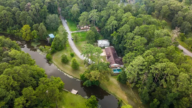 an aerial view of residential house with outdoor space and trees all around