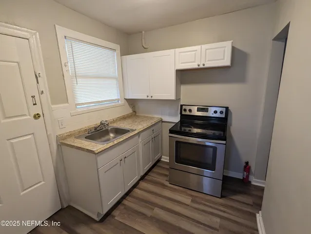 a kitchen with granite countertop white cabinets and stainless steel appliances