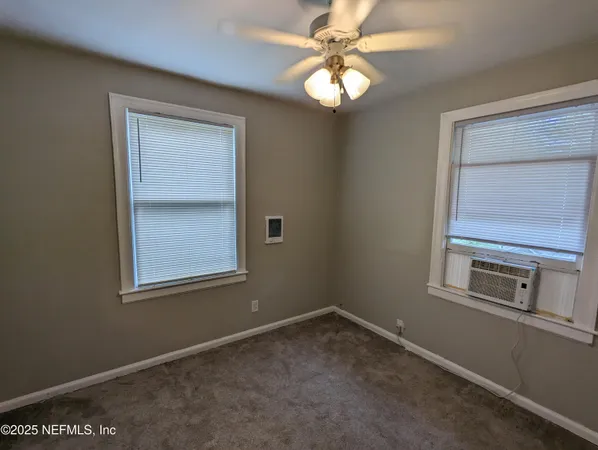 an empty room that has a window and a fan