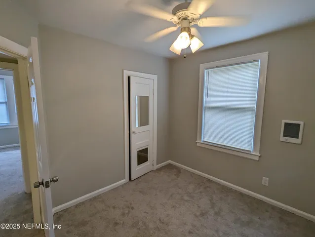 an empty room with closet and a chandelier fan