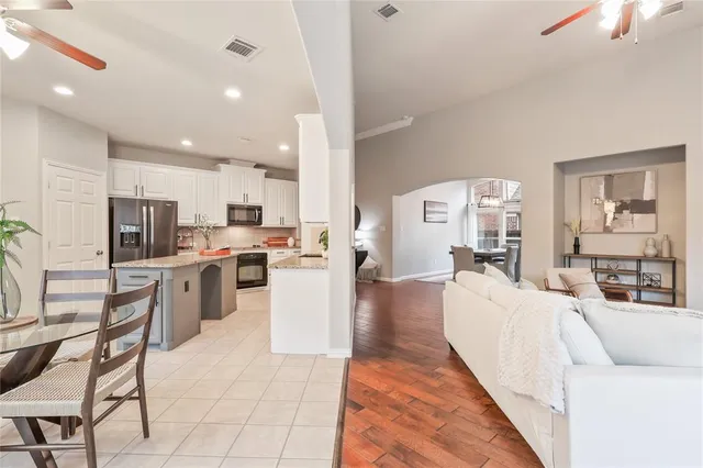 a living room with stainless steel appliances furniture a rug and a kitchen view