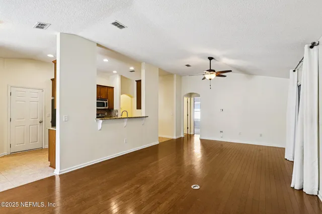 a view of a kitchen with wooden floor a ceiling fan and kitchen view