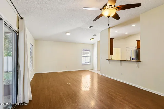 a view of an empty room with window and wooden floor