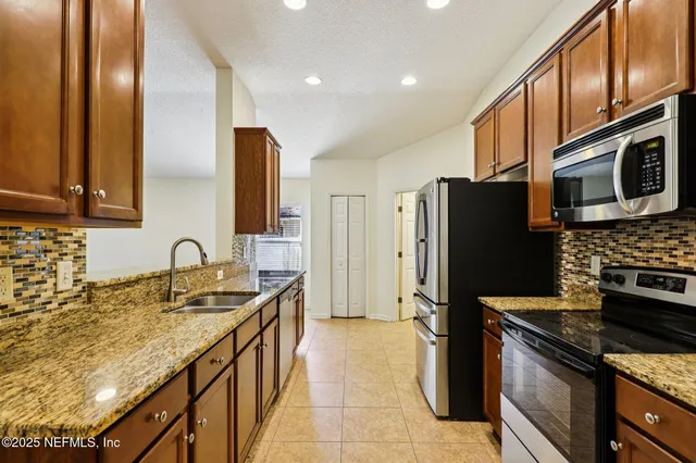 a kitchen with granite countertop a refrigerator stove and microwave