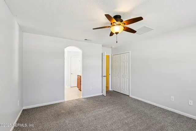 an empty room with windows and fan